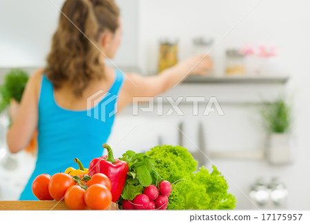 Closeup on vegetable and young housewife in background Closeup on vegetable and young housewife in background 17175957
