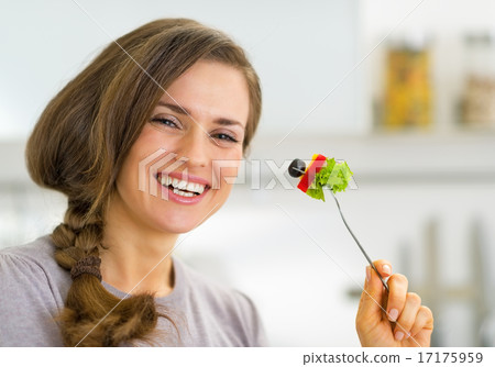 Portrait of smiling young housewife eating vegetables Portrait of smiling young housewife eating vegetables 17175959