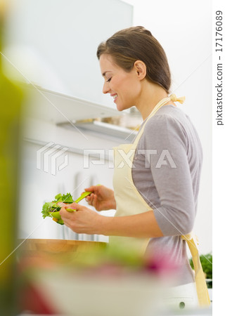 Happy young housewife mixing salad in modern kitchen 17176089
