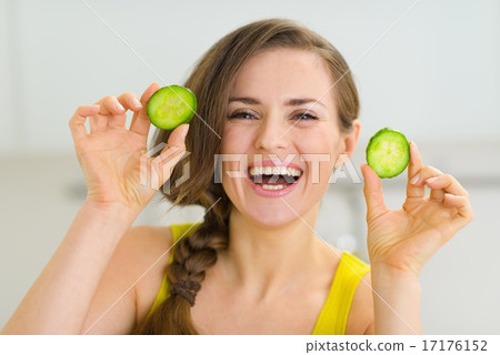 Smiling young woman showing slices of cucumber 17176152