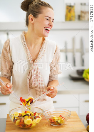 Happy young housewife mixing fruits salad Happy young housewife mixing fruits salad 17176153