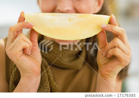 Closeup on young woman holding melon slice in front of mouth 17176385