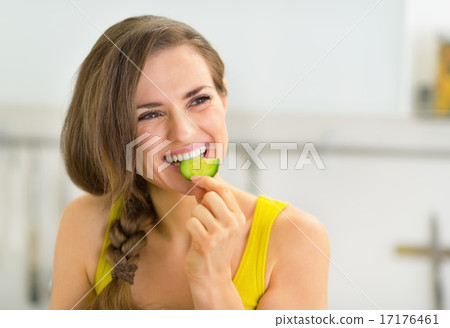 Portrait of young woman eating cucumber in kitchen Portrait of young woman eating cucumber in kitchen 17176461