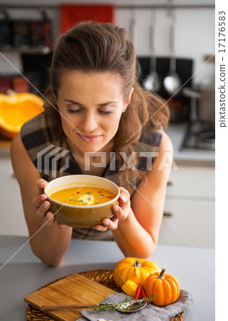 Young woman enjoying pumpkin soup in kitchen 17176583