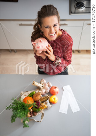 Happy young housewife showing piggy bank after local market shop 17176750