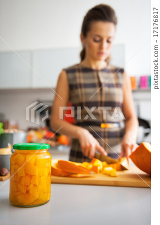 Closeup on jar of pickled pumpkin and young housewife cutting in 17176817