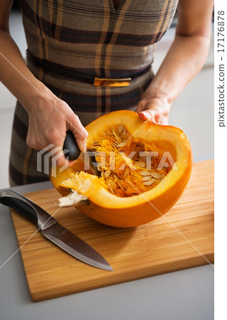 Closeup on young housewife removing filling from pumpkin Closeup on young housewife removing filling from pumpkin 17176878