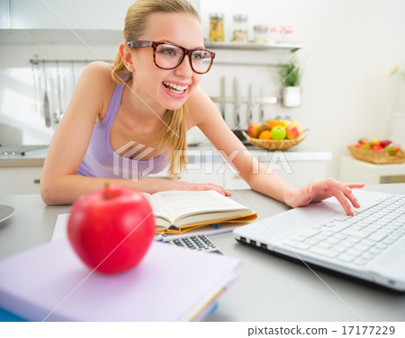 Happy young woman studying in kitchen 17177229