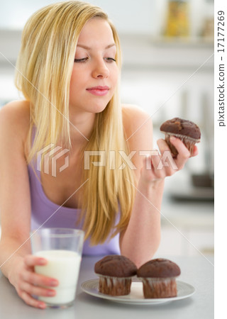 Teenager girl eating muffin with milk in kitchen Teenager girl eating muffin with milk in kitchen 17177269