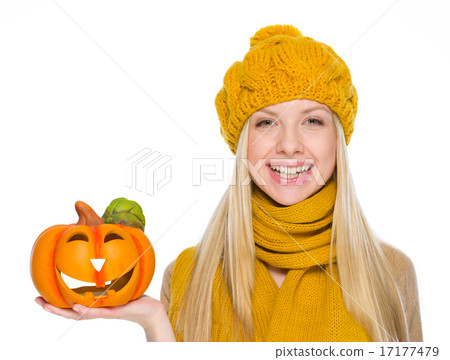 Happy girl in hat and scarf holding jack-o-lantern Happy girl in hat and scarf holding jack-o-lantern 17177479