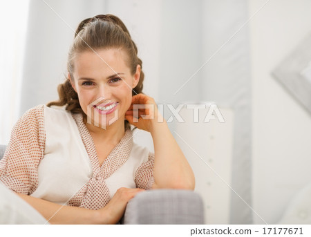 Portrait of smiling young housewife in living room Portrait of smiling young housewife in living room 17177671