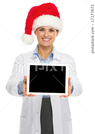 Smiling doctor woman in santa hat showing tablet pc blank screen Smiling doctor woman in santa hat showing tablet pc blank screen 17177672
