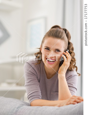 Happy young woman talking mobile phone in living room Happy young woman talking mobile phone in living room 17177753