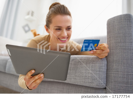 Closeup on credit card in hand of young woman laying on sofa wit Closeup on credit card in hand of young woman laying on sofa wit 17177754