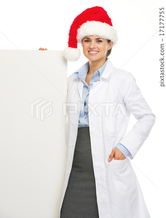 Happy doctor woman in santa hat showing blank billboard Happy doctor woman in santa hat showing blank billboard 17177755