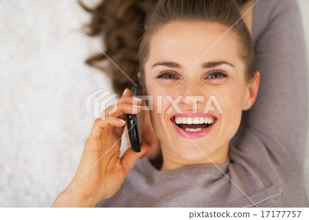 Young woman talking mobile phone while laying on floor 17177757