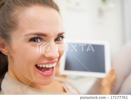 Funny portrait of smiling young woman sitting on divan and using Funny portrait of smiling young woman sitting on divan and using 17177761