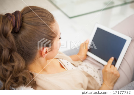 Young woman sitting on divan and using tablet pc . rear view Young woman sitting on divan and using tablet pc . rear view 17177782