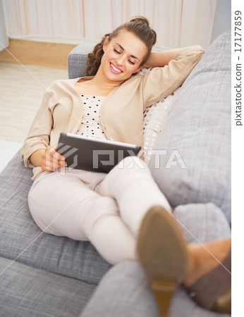 Happy young woman laying on divan and using tablet pc Happy young woman laying on divan and using tablet pc 17177859