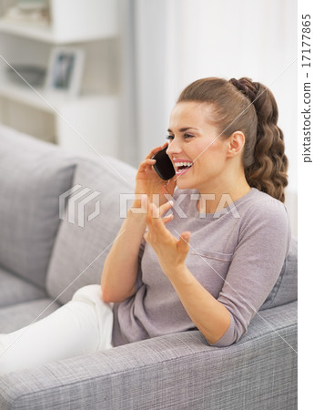 Happy young woman talking mobile phone in living room Happy young woman talking mobile phone in living room 17177865