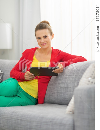 Young woman sitting on sofa and using tablet pc Young woman sitting on sofa and using tablet pc 17178014