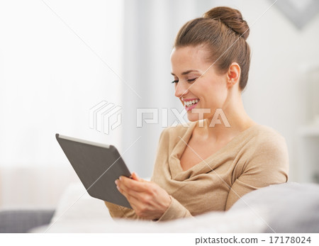 Happy young housewife sitting on sofa and using tablet pc Happy young housewife sitting on sofa and using tablet pc 17178024