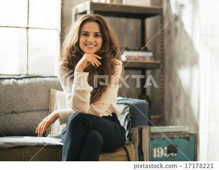 Happy young woman sitting in loft apartment Happy young woman sitting in loft apartment 17178221