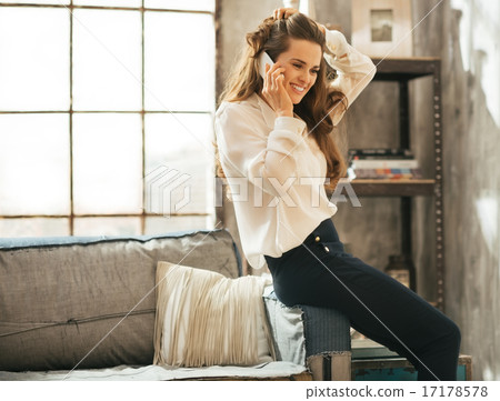 Happy young woman talking mobile phone in loft apartment Happy young woman talking mobile phone in loft apartment 17178578