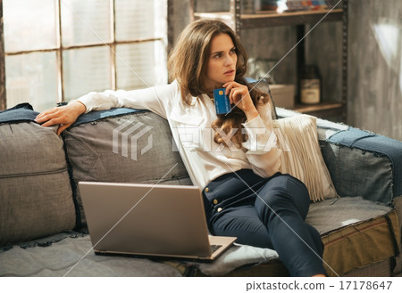 Thoughtful young woman with credit card making online shopping Thoughtful young woman with credit card making online shopping 17178647