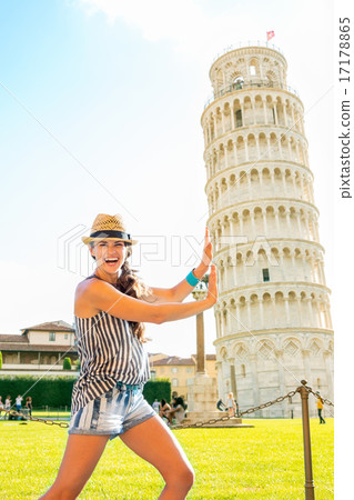 Funny young woman supporting leaning tower of pisa, tuscany, ita 17178865