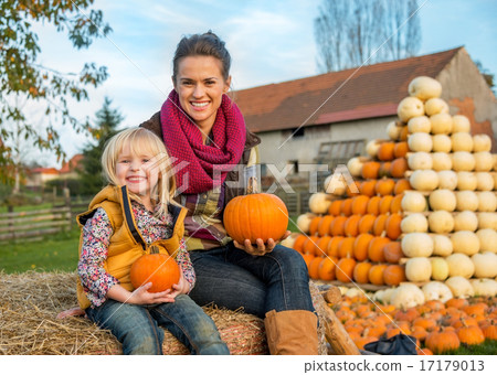 Portrait of happy mother and child sitting on haystack and holdi 17179013