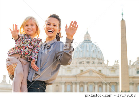 Portrait of happy mother and baby girl waving in front of basili 17179108