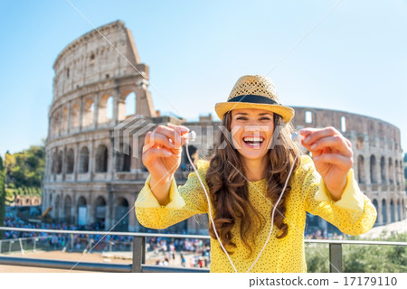 Happy young woman giving headphones with audio guide in front of 17179110