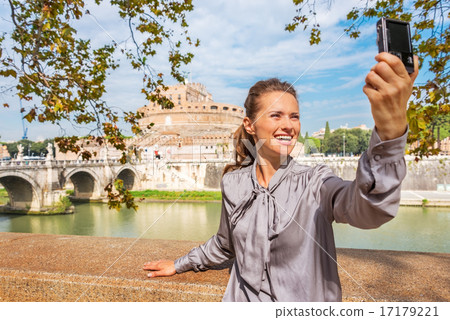 Smiling young woman making selfie on embankment near castel sant Smiling young woman making selfie on embankment near castel sant 17179221