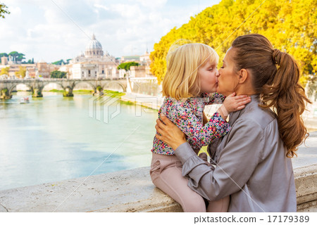 Mother and baby girl kissing on bridge ponte umberto I with view 17179389