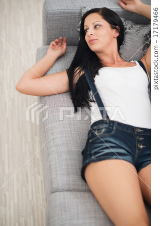 Thoughtful young woman laying on couch Thoughtful young woman laying on couch 17179466
