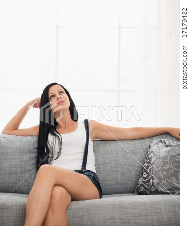 Thoughtful girl sitting on couch in living room 17179482