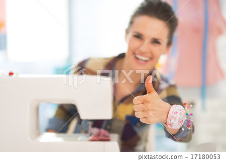 Closeup on seamstress with sewing machine showing thumbs up Closeup on seamstress with sewing machine showing thumbs up 17180053