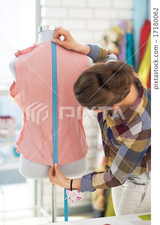 Tailor woman working with dress in studio. rear view 17180062
