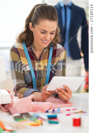Happy seamstress using tablet pc at work Happy seamstress using tablet pc at work 17180114