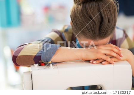 Stressed seamstress near sewing machine Stressed seamstress near sewing machine 17180217