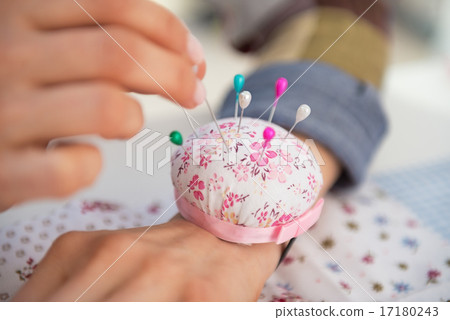 Closeup on seamstress putting needle in pincushion Closeup on seamstress putting needle in pincushion 17180243