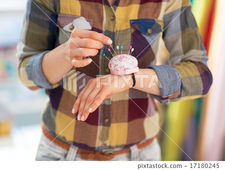 Closeup on seamstress putting needle into pincushion Closeup on seamstress putting needle into pincushion 17180245