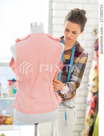 Seamstress adjusting clothing on mannequin Seamstress adjusting clothing on mannequin 17180255