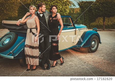 Wealthy friends near classic convertible 17182820