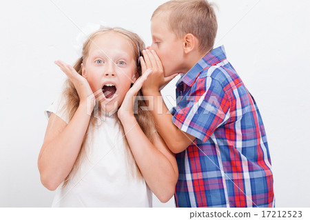 Teenage boy whispering in the ear a secret to teen girl on white  background 17212523