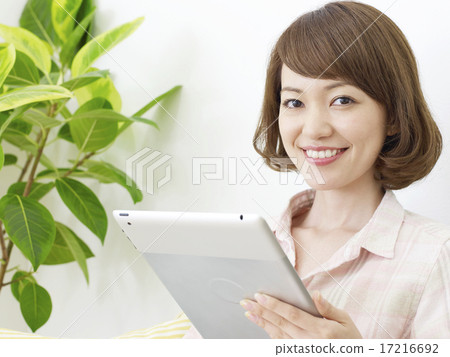 使用片劑的一名婦女在屋子裡 使用片劑的一名婦女在屋子裡 17216692