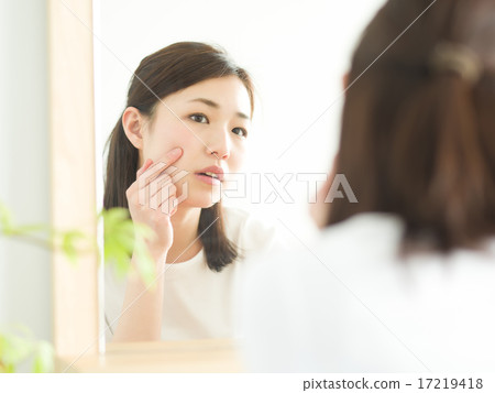 A young lady looking at a beauty mirror 17219418