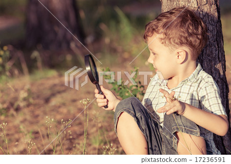 Happy little boy exploring nature with magnifying glass 17236591