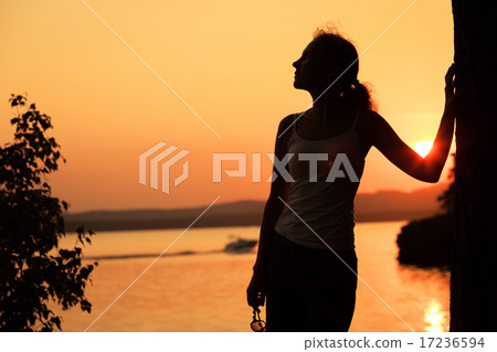 Silhouette of happy woman who standing on the coast of lake 17236594